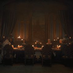 a group of people sitting around a table with candles