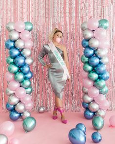 a woman standing in front of balloons and streamers