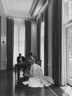 a woman sitting at a table in front of a window next to a man on a chair