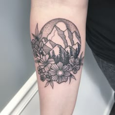 a woman's arm with flowers and mountains on it