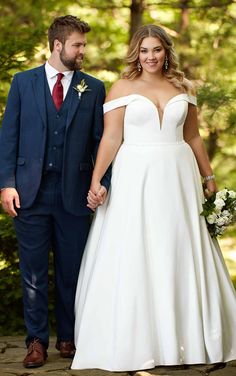 a bride and groom holding hands while walking through the woods on their wedding day,