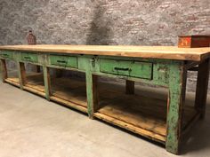 an old wooden table with two drawers on one side and a potted plant on the other