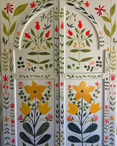 an intricately painted door with flowers and leaves on the outside, in front of a white wall