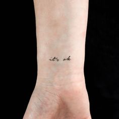 a small wrist tattoo saying it's ok on the left side of the arm