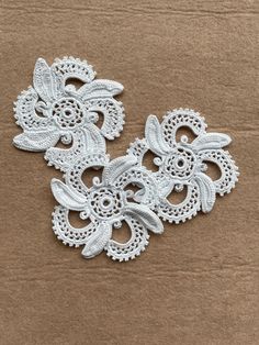 three white lace appliques sitting on top of a cardboard box