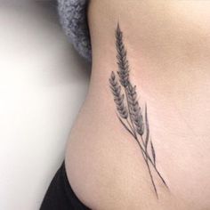 a woman's stomach with a small tattoo of two plants on the side of her belly