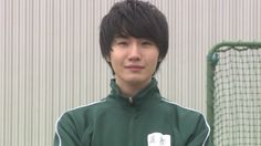 a young man standing in front of a soccer goal wearing a green and white jacket