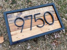 a wooden sign with the number seventy seven on it sitting in grass next to leaves