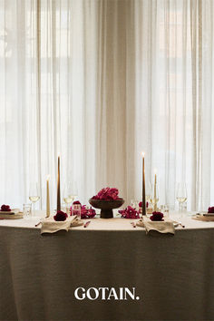 A Christmas-themed dining room with a festive table setting, a glowing Christmas tree, and sheer linen curtains in sand filtering soft natural light.