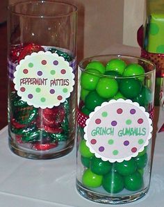 two glass vases filled with green and red candies on top of a table