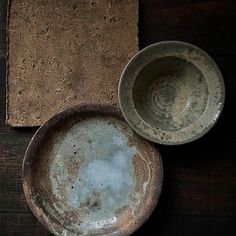 two dirty bowls sitting on top of a wooden table next to a towel and placemat