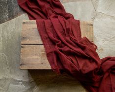 a piece of wood sitting on top of a stone wall next to a red cloth