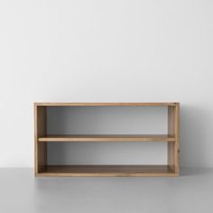 an empty wooden shelf against a white wall