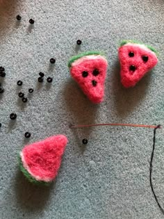 three watermelon slices are sitting on the floor next to some beads and thread