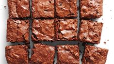 chocolate brownies are arranged in rows on a white surface with one being cut into squares