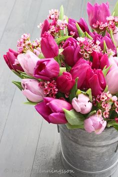 a bucket filled with pink flowers on top of a wooden floor