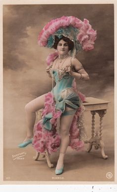 an old fashion photo of a woman in a dress and hat with feathers on her head