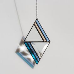 a blue and white necklace hanging from a chain on a wall with an abstract design