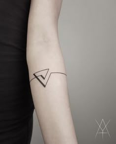 a woman's arm with a small black arrow tattoo on it