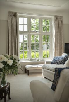 a living room filled with furniture and a large window next to a white couch covered in pillows