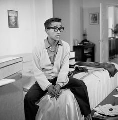 a black and white photo of a man sitting on a bed