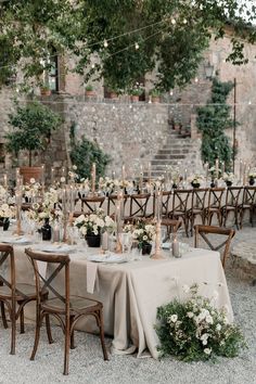 an outdoor table set up with flowers and candles for a wedding reception in the countryside