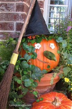 a pumpkin sitting in a flower pot with a broom sticking out of it's mouth