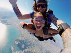 a man and woman are skydiving in the air with their arms around each other