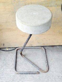 a white stool sitting on top of a metal stand next to a wooden wall and power cord