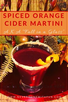 an orange cider martini in a glass on top of a wooden table with leaves