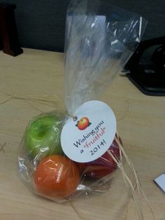 an apple, oranges and apples wrapped in plastic on a wooden table with a name tag