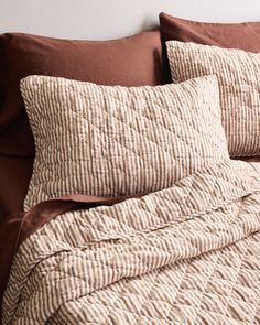 a bed with brown and white comforter next to a pillow on top of it