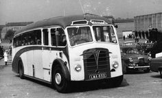 an old black and white photo of a bus on the street with other cars in the background