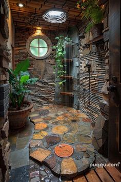 a bathroom with stone walls and flooring next to a shower stall filled with plants