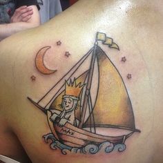 a man with a tattoo on his back that has a cat in a sailboat