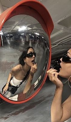 a woman taking a selfie in front of a large round mirror with her reflection