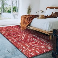 a bedroom with an orange rug on the floor and a bed in front of a large window