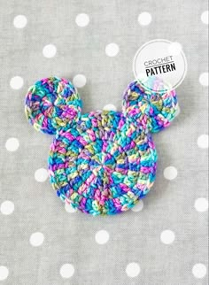 a crocheted mickey mouse pin sitting on top of a polka dot fabric