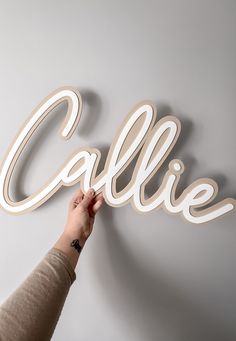 a person is writing the word callie on a wall with white paint and wood letters