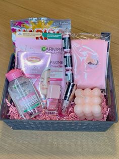 an open box with various items in it on a wooden table and some pink tissue