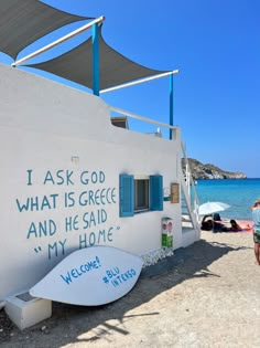 a white building with blue shutters on the side and a surfboard leaning against it