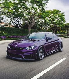 a purple car is driving down the road with trees in the backgrouund