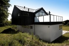 a black and white house sitting on top of a lush green field