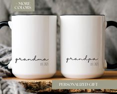 two personalized coffee mugs sitting on top of a wooden table next to a blanket