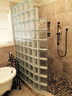 a glass block shower in a bathroom next to a tub