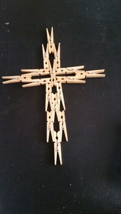 a cross made out of clothes pins on a black surface