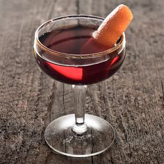 a close up of a wine glass with a drink in it on a wooden table