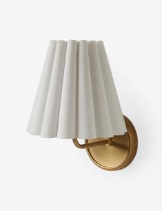 a wall light with a white shade on it's side and a gold finish