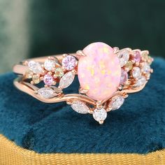 an opal and diamond ring sits on top of a blue velvet cushioned box