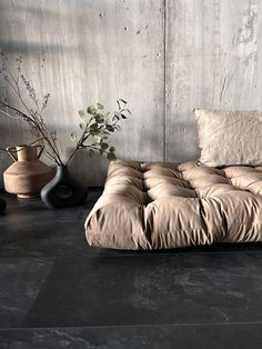 a bed sitting next to two vases on top of a floor